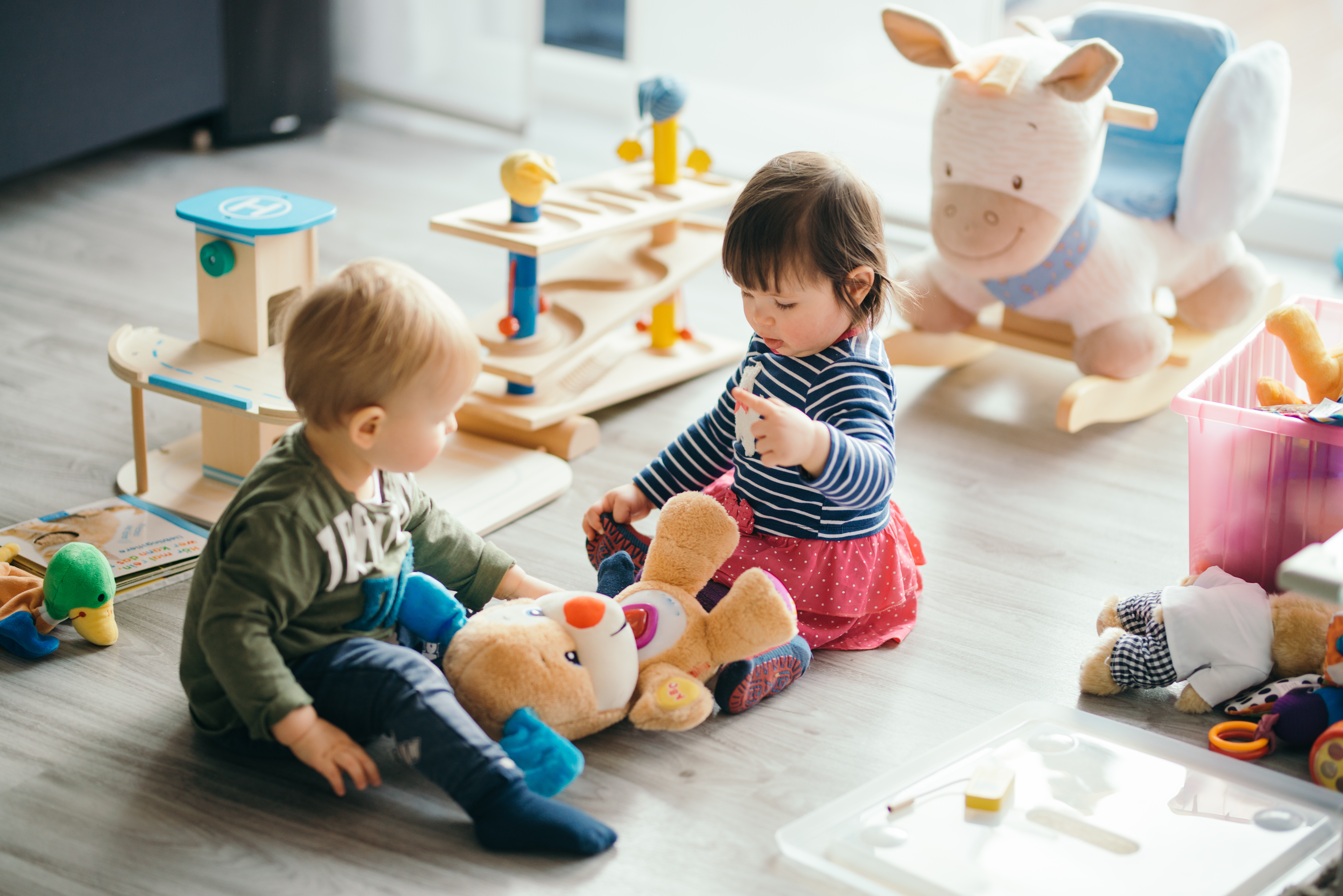 Deux enfants jouent avec un ourson dans une micro-crèche