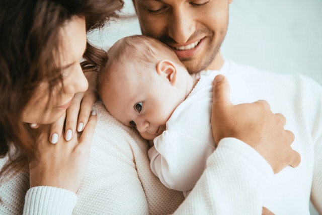 Les parents font un câlin à leur bébé.